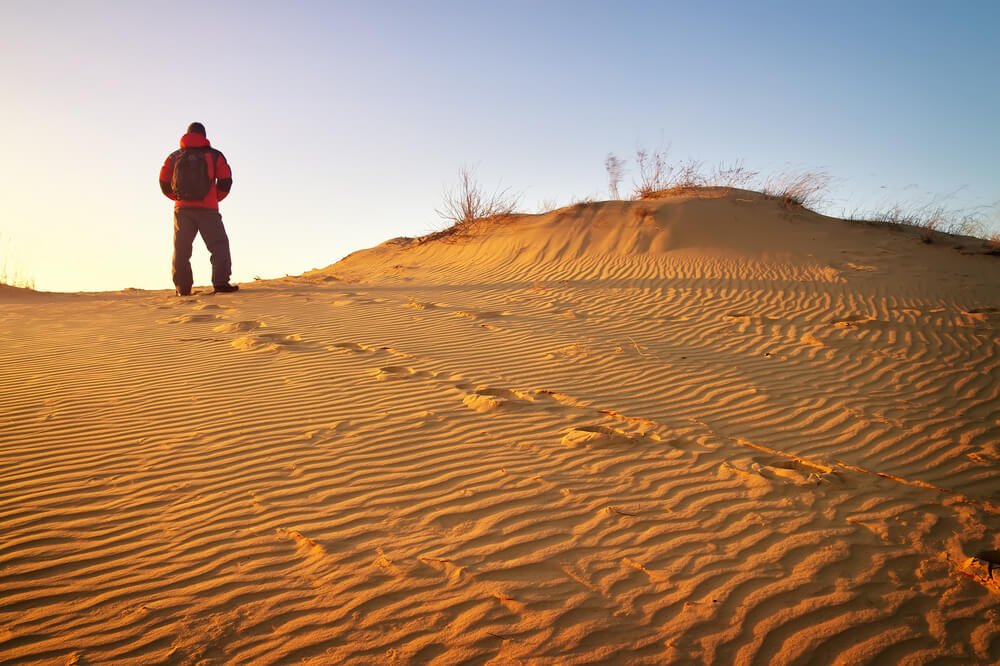 Man wearing winter clothes standing in the Sahara dunes