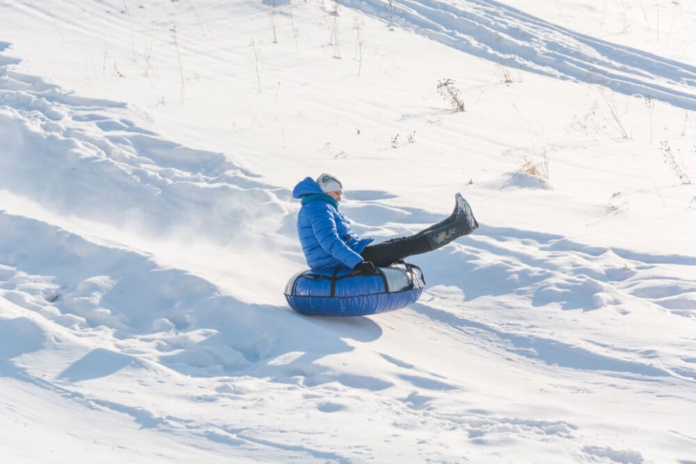 Children riding on an inflatable snow tube in Rocky Mountain national park in winter