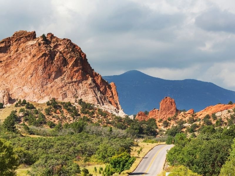 Road leading to Garden of the Gods park in Colorado Springs with green trees and red rocks