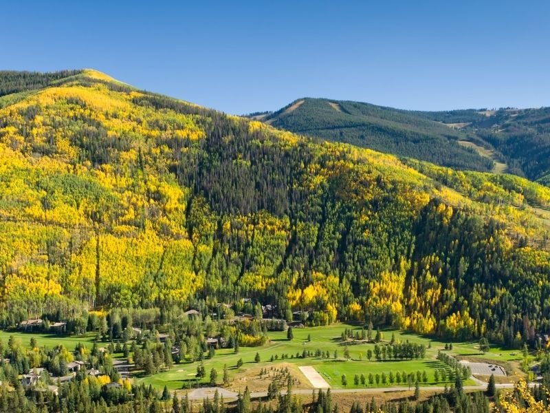 the beautiful mountain town of vail colorado with yellow aspen trees around it