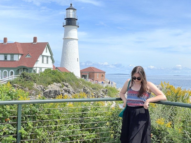 allison standing in front of portland head light house on a sunny day in summer