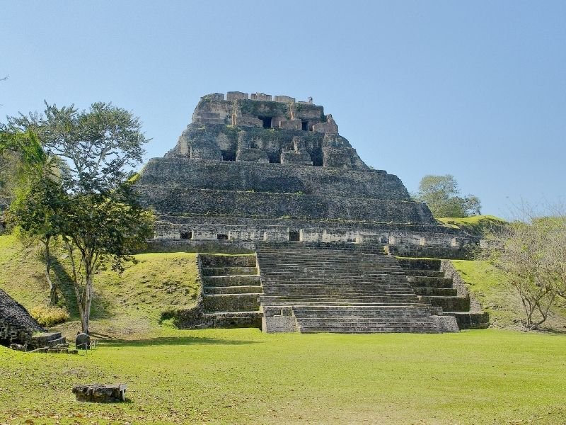 the largest stone structure at xunantunich surrounded by grass, trees, etc