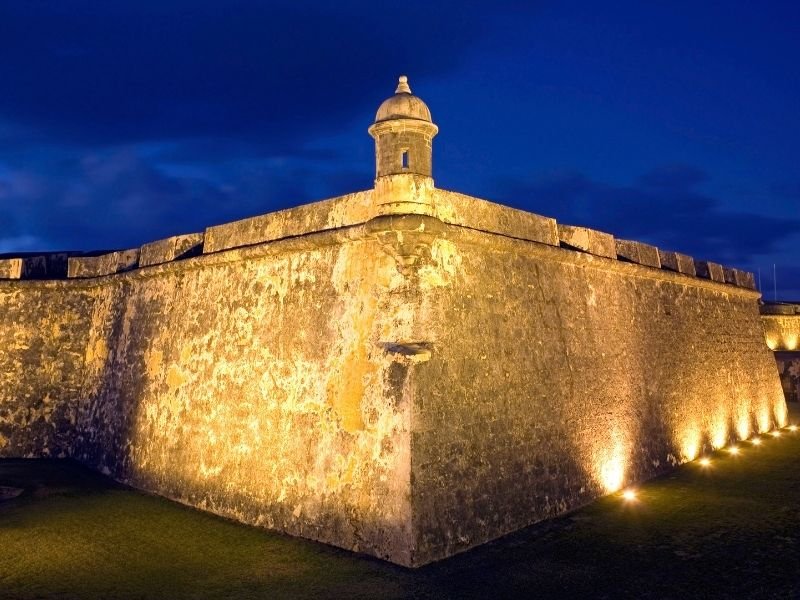 lit up fort of el morro at night with a dark blue sky