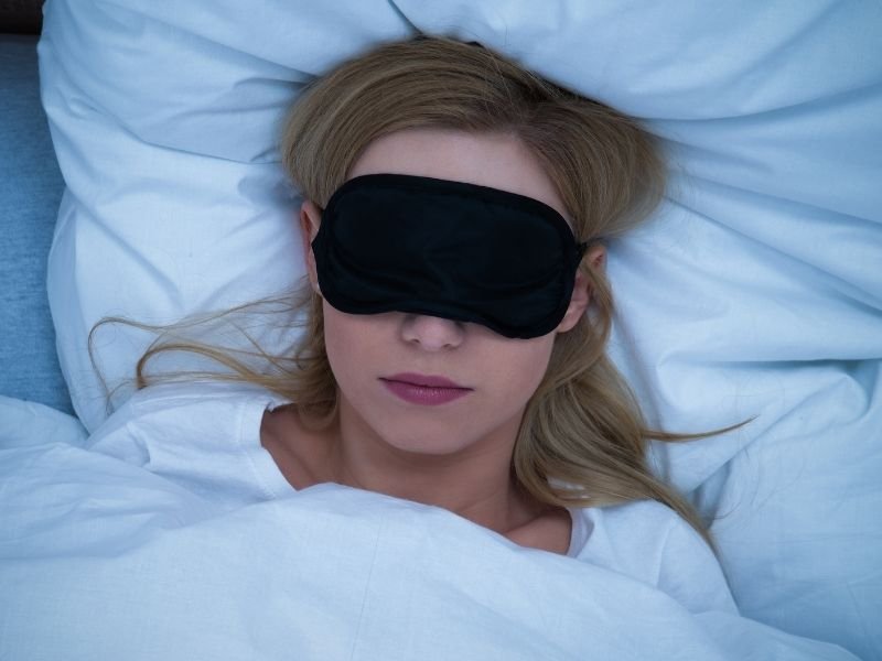 woman wearing an eye mask laying in bed