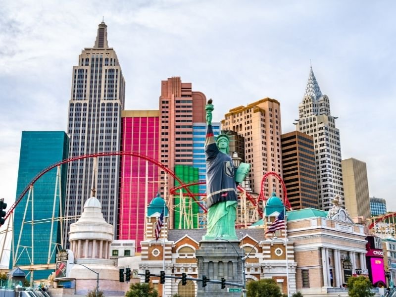 The roller coaster in front of the new york new york hotel in las vegas with the statue of liberty in front