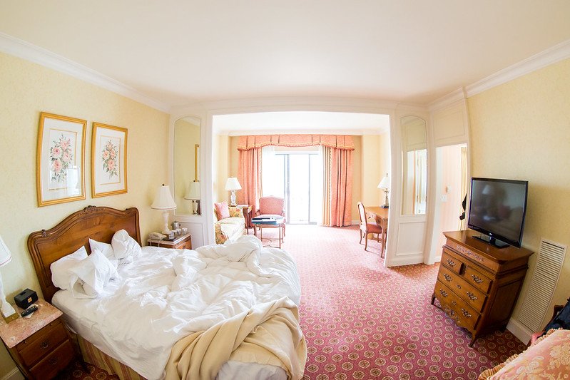 interior of the grand america hotel with pink carpeting, an unmade bed, and spacious suite area