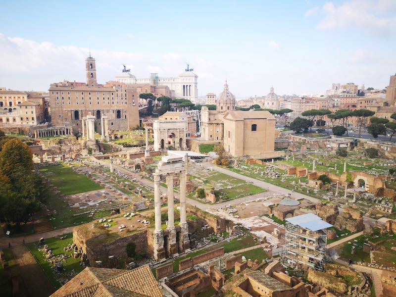 The ruins of the Roman forum spread out over this Rome landmark with arches, ancient streets, etc. in the middle of the modern city of Rome