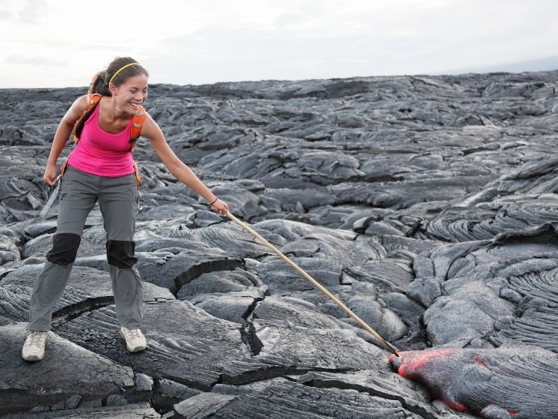 traveler poking molten hot lava at volcanoes national park