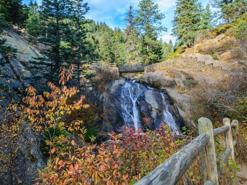 the cascading waterfall of helen hunt fall with a footbridge above it in colorado springs co