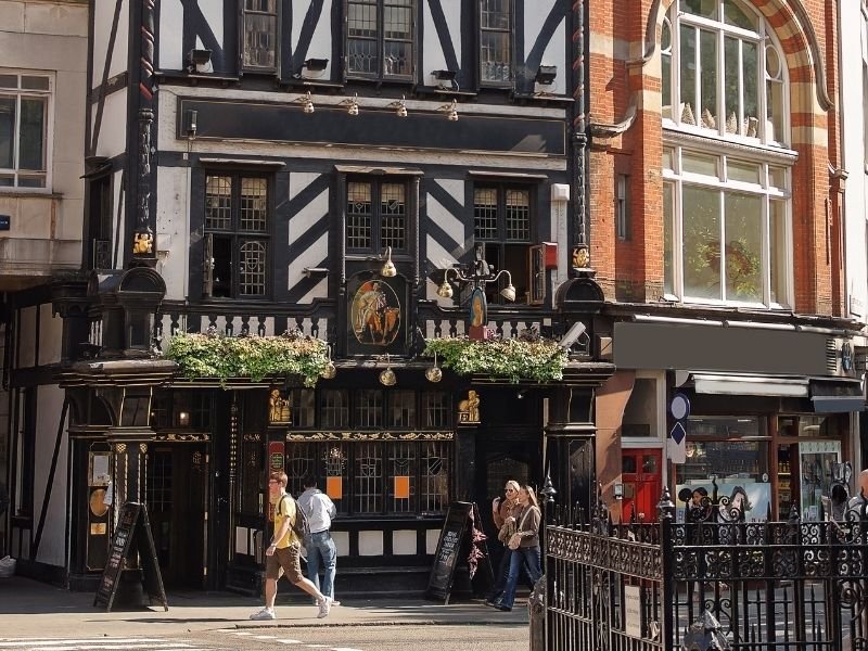 london pub with a beautiful facade and people walking in front of it