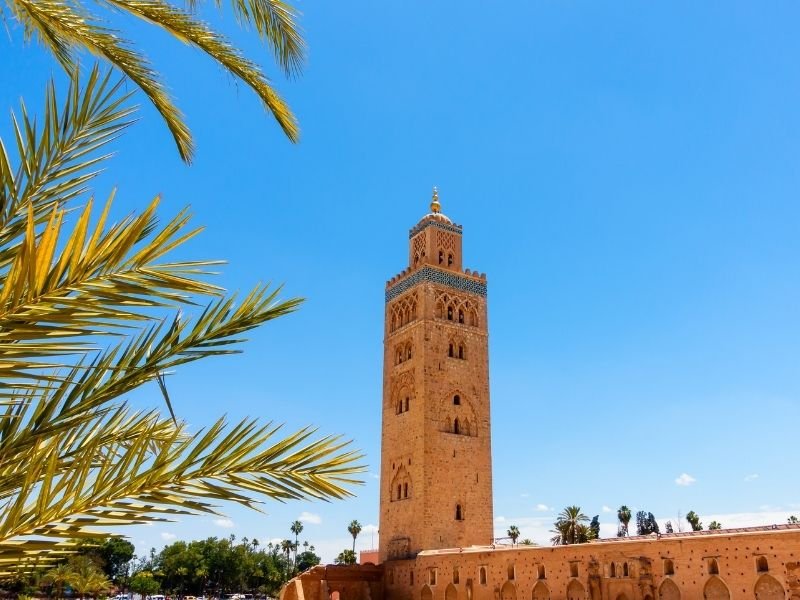 large minaret in marrakech and palm fronds