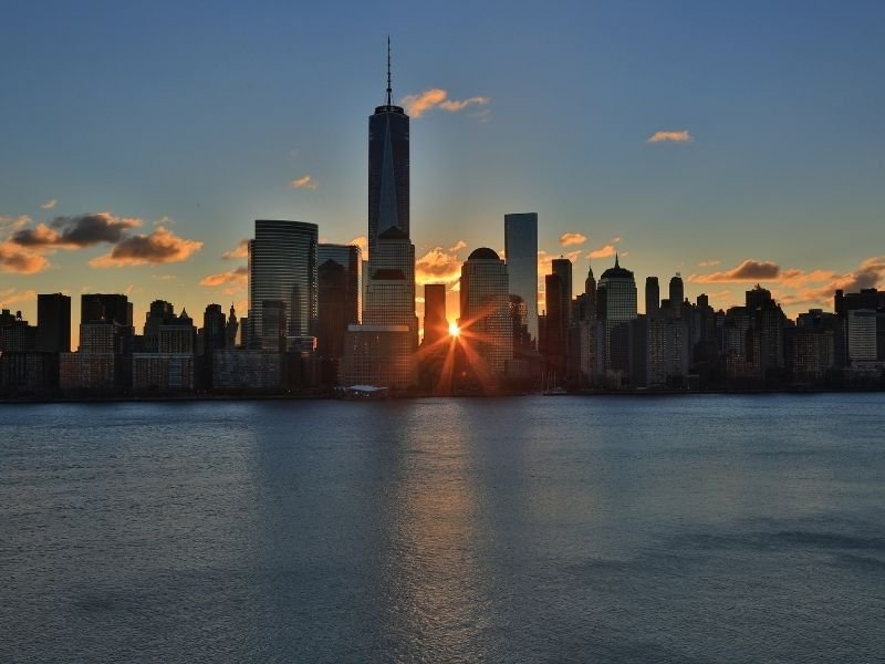 the sun setting between buildings creating a sunburst in new york city 