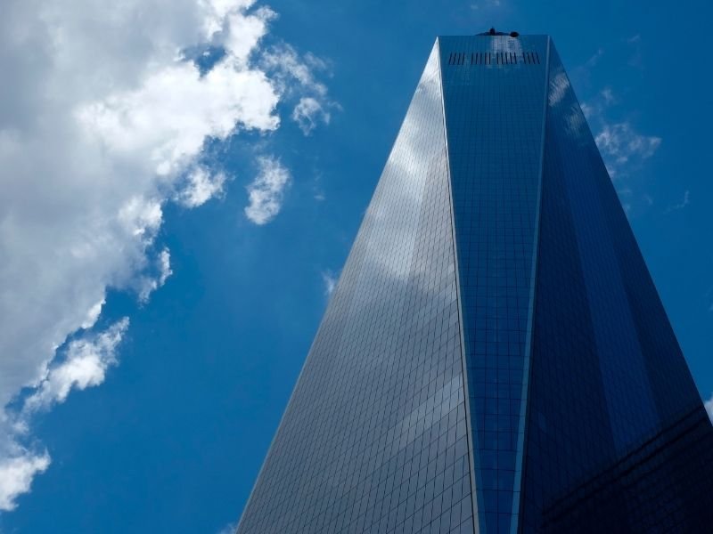 view looking up towards the one world observatory building on a cloudy day