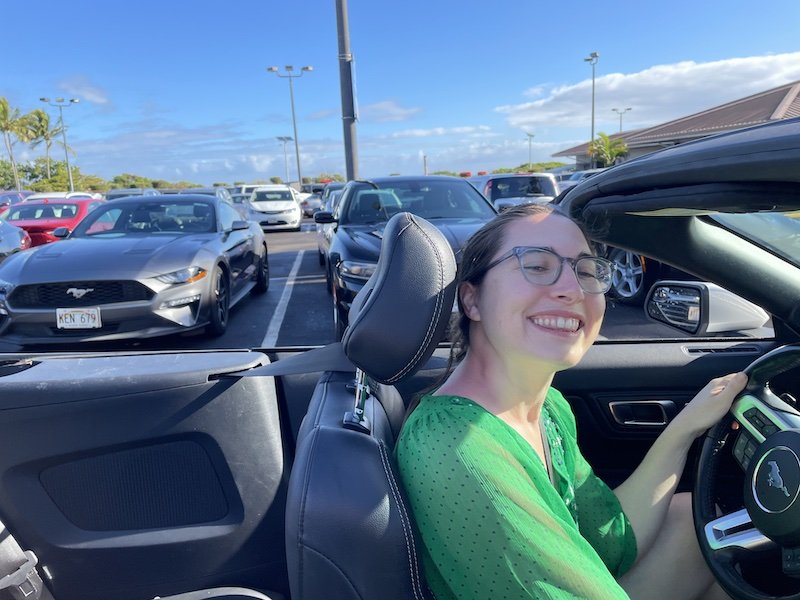 Allison smiling in a convertible in a rental car place