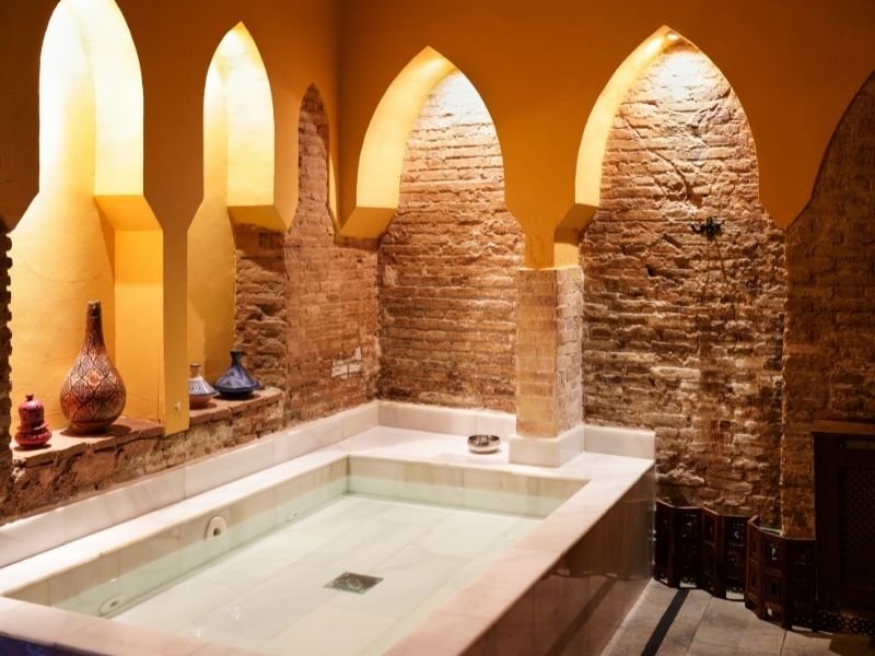small bath in a brick room with arches and pottery in a traditional arabic style hammam in granada