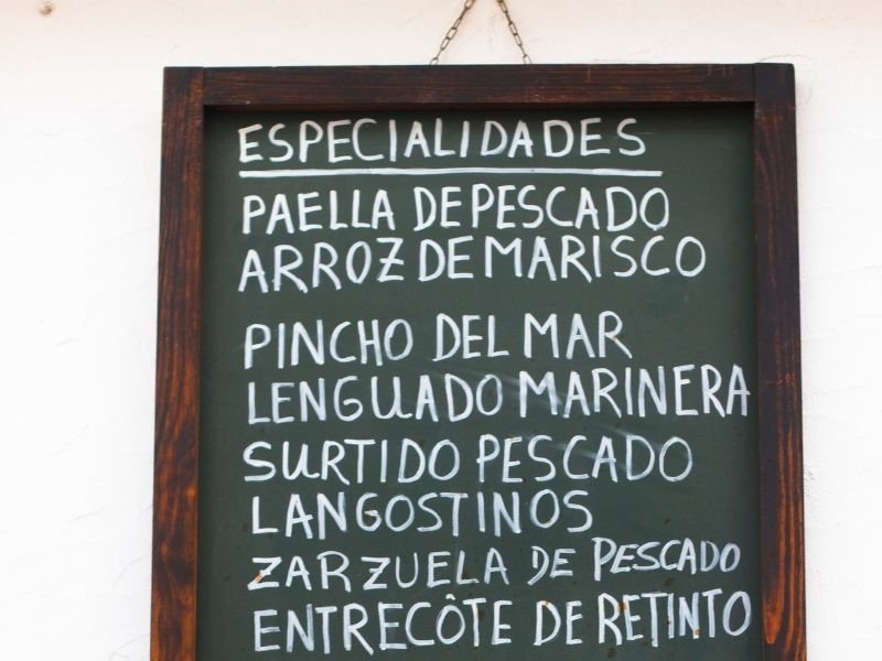 sign with various spanish dishes including fish paella and seafood rice