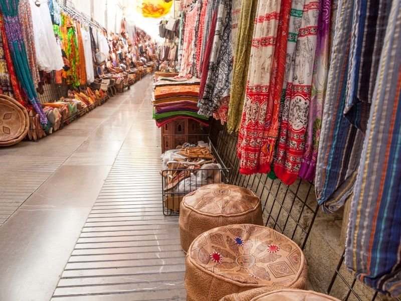 Leather puffs to sit on and textiles for sale in an alleyway in the Alcaiceria in Granada, Spain