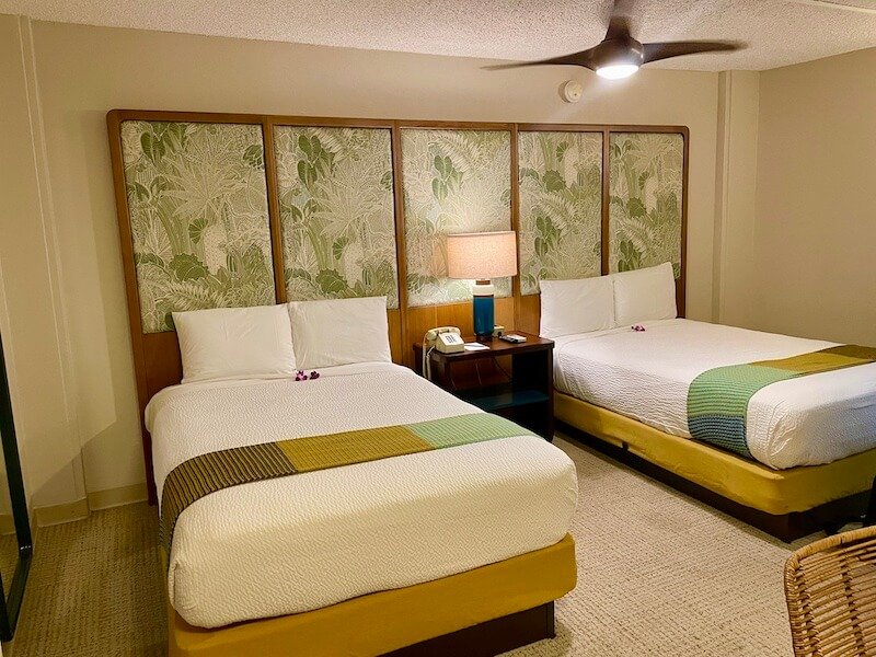 Two beds against a vintage wallpaper headboard in a redesigned hotel called the White Sands located in Waikiki honolulu