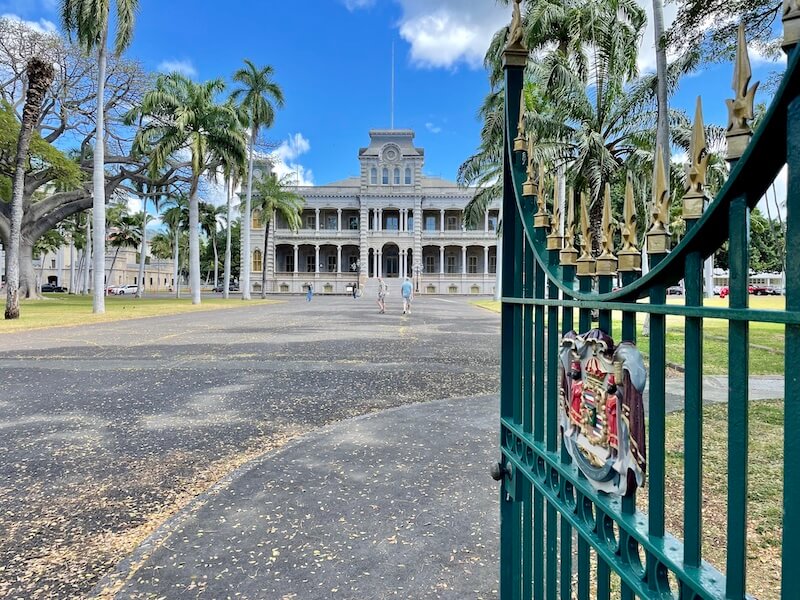 open gate leading to a pathway showing iolani palace, a royal residence turned house museum