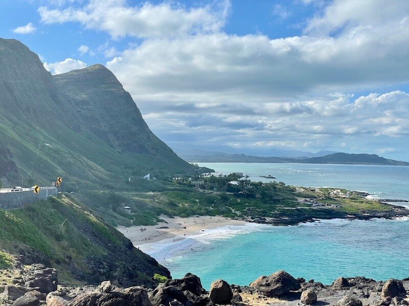 the beautiful makapuu lookout with views over the beach and road and mountains on a sunny day with some clouds
