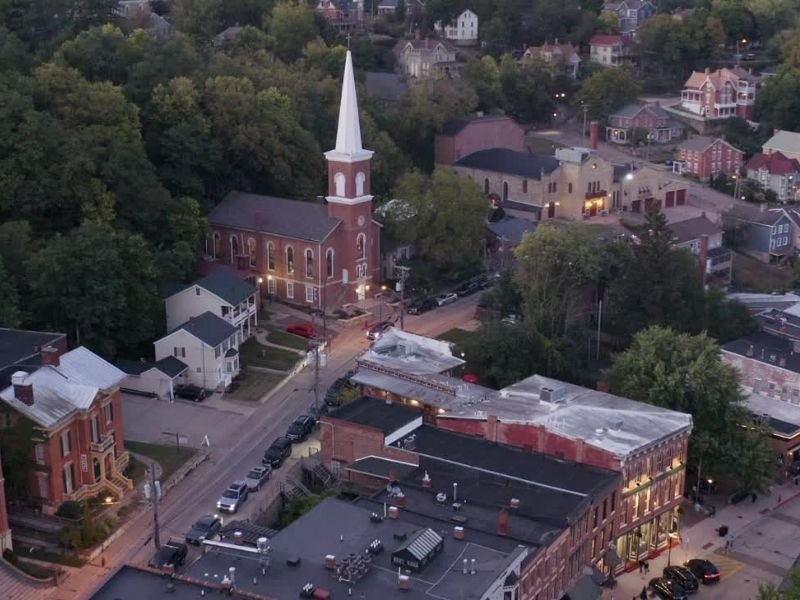 Drone photo over the downtown of Galena Illinois showing a church and historic buildings at twilight with lights on