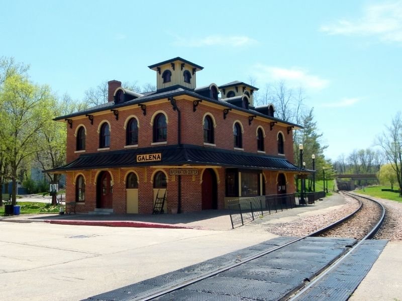 A historic railroad depot that reads "GALENA" and another sign that reads "INFORMATION CENTER" with a track running through the town