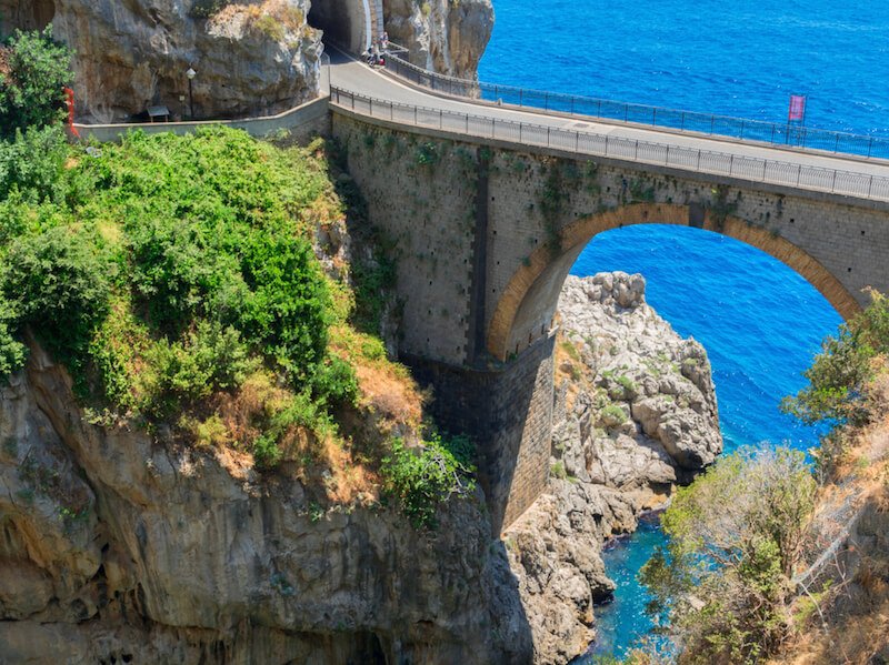 bridge on the amalfi coast going over water below and sea in the distance