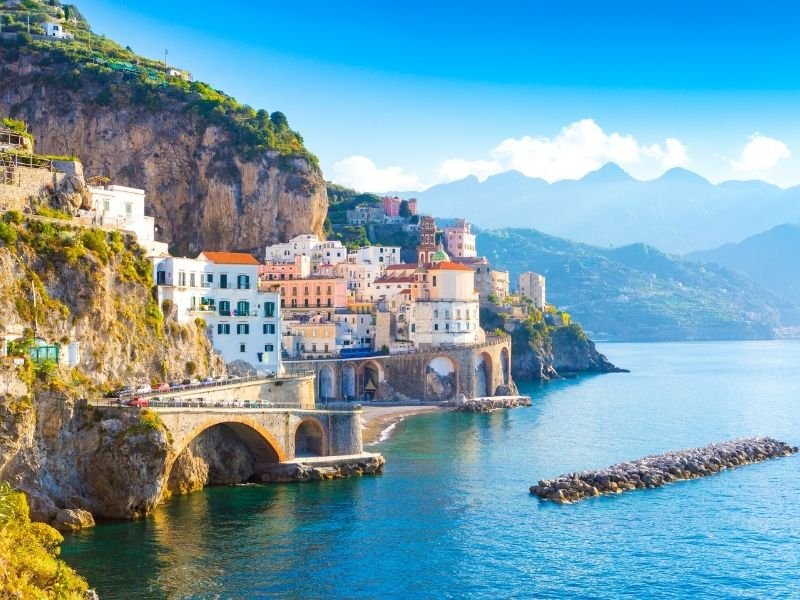 the town of amalfi italy seen with a bridge, clear water, and colorful buildings