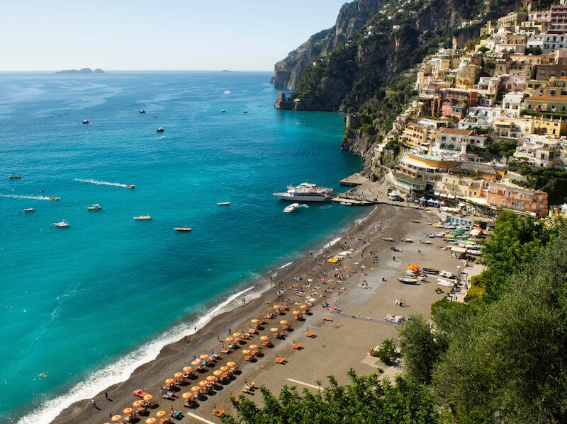 the beautiful beach in positano with its telltale umbrellas and blue sea and lots of small boats