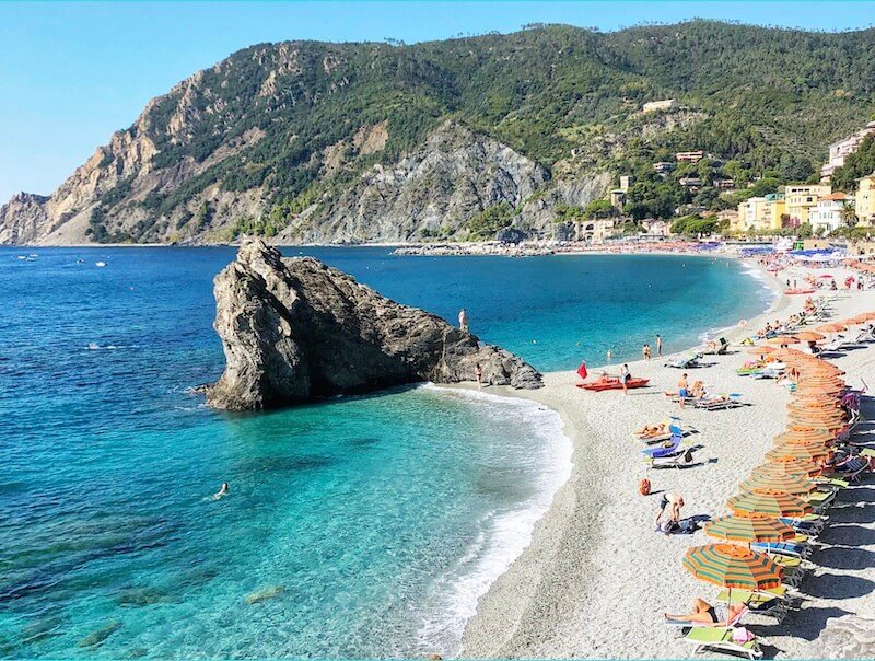 the famous beach of spiaggina fegina in monterosso al mare with the telltale orange and teal umbrellas