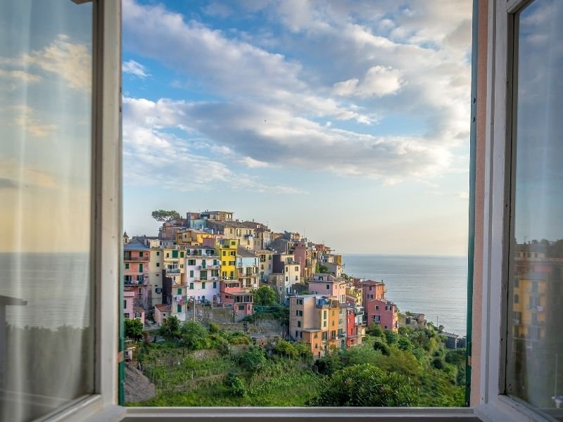 view of the town of corniglia as seen through the open windows of a hotel room