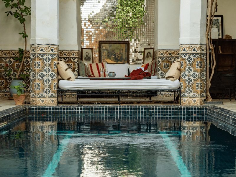 a charming plunge pool in a riad in fes with a couch at the end where people can lounge and relax at the end of a day exploring morocco