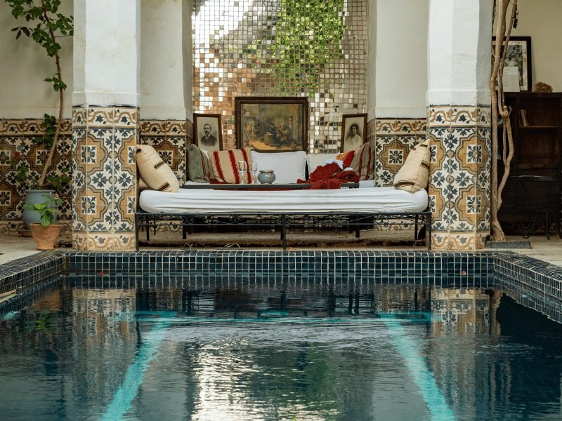 a charming pool in a riad in marrakech with a seating area and mosaic tilework