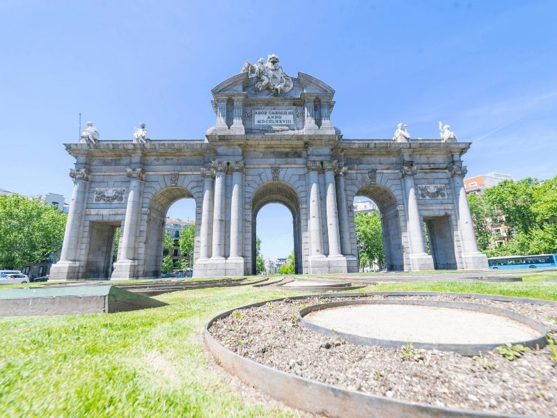 five arches of the puerta de alcala with ornate sculpturework and text in roman numerals near el retiro park