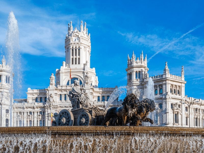 the plaza of cibeles with a fountain and palace behind it which is now the madrid city council -- all famous landmarks of madrid and must sees on a madrid itinerary