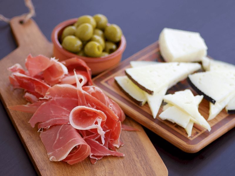 spanish ham, cheese, and olives on plates