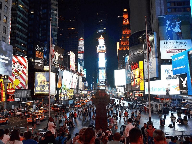 crowds of people and bright neon lights in new york city's time square