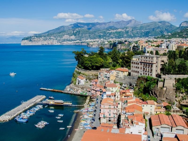 the red rooftops of the buildings in sorrento italy and the harbor and blue sea and cliffs in the distance