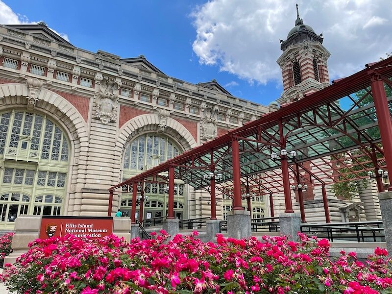 view of pink flowers in front of the ellis island national monument building and museum