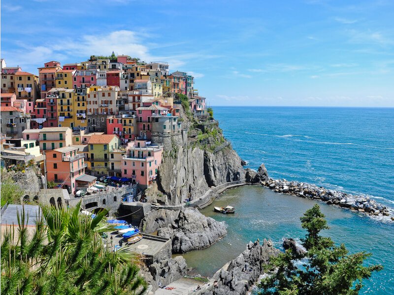 the beautiful harbor of manarola as seen from above with colorful houses and blue waters