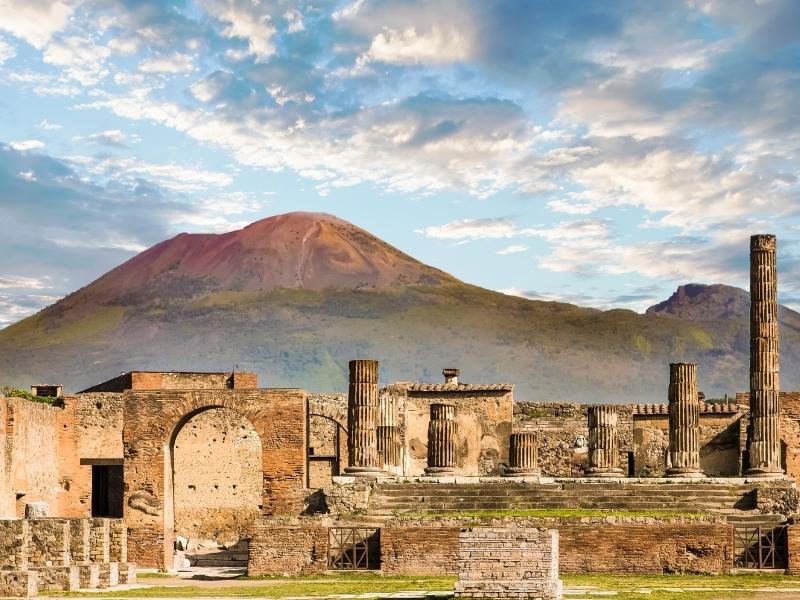 view of pompeii with mt vesuvius in the background with ruins 