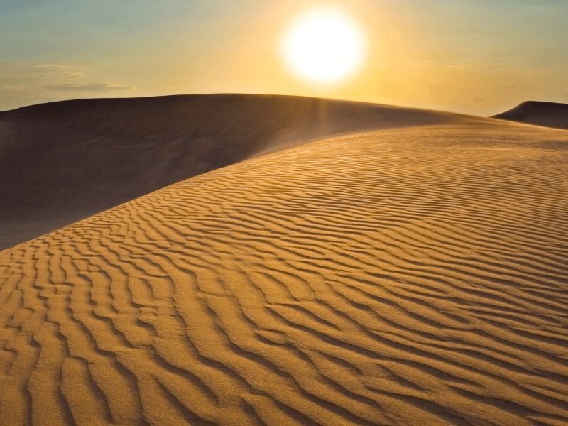 sun setting over the rippled sand dunes in the dubai desert