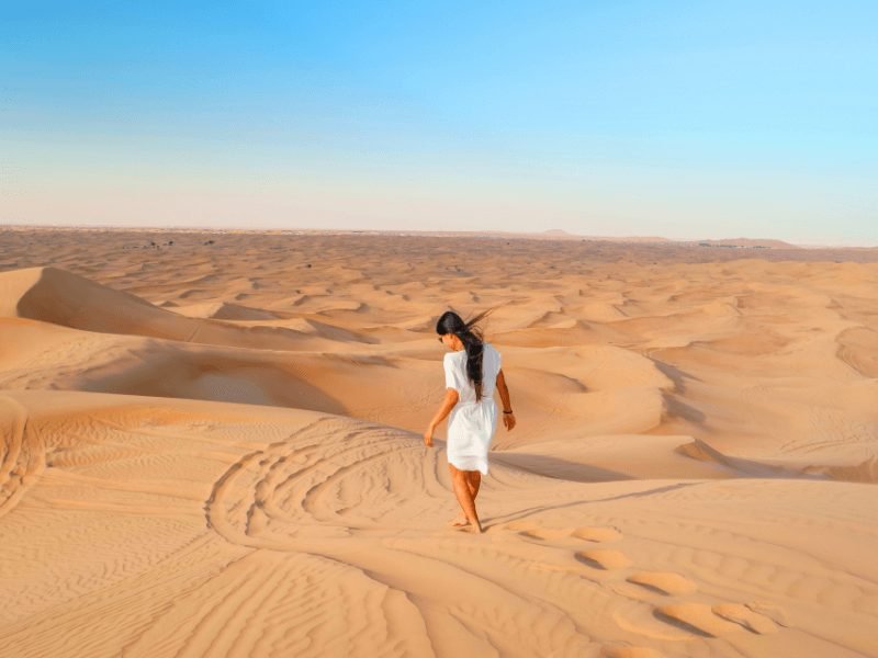 woman walking in the dubai desert facing away from the camera