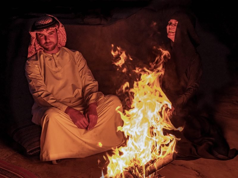 people in traditional emirati dress around the fire