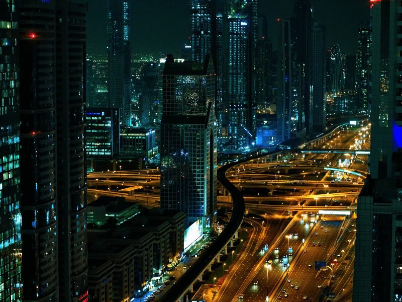 view of dubai at night with cars on the highway