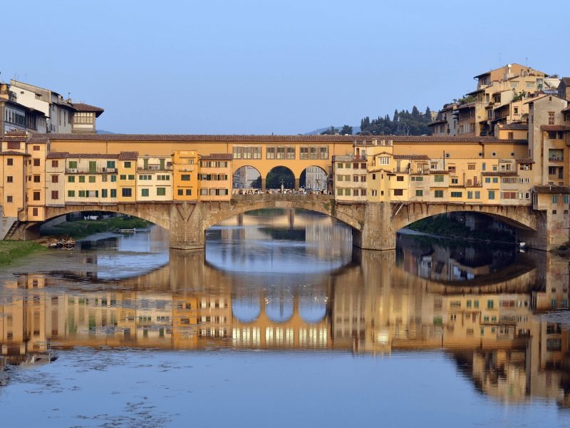 the covered bridge of the ponte vecchio with several stone arches going over the arno river in florence italy