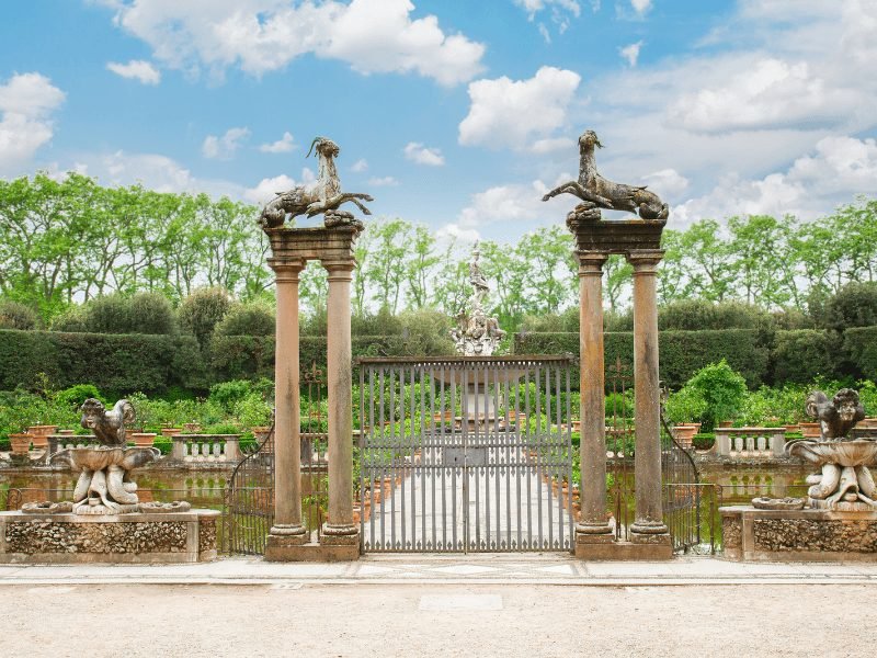 a gated area in the boboli gardens with greenery and sculptures