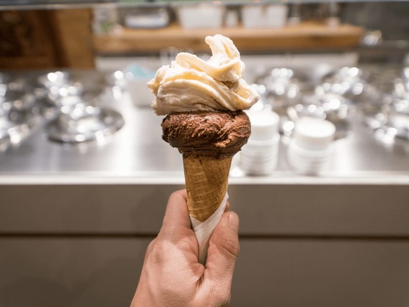 hand holding a chocolate and vanilla two scoop gelato cone