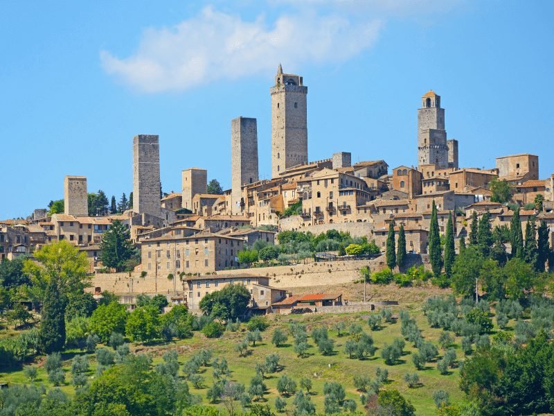 view of the city of san Gimignano with its medieval stone towers protruding from the rest of the skyline of the hillside town