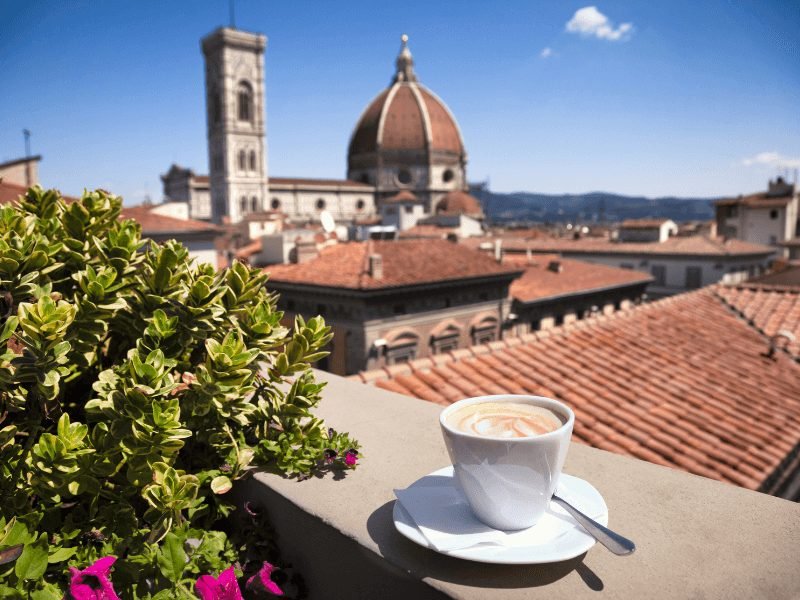 a small cappuccino enjoyed outdoors on a rooftop terrace with a view of the duomo in the distance